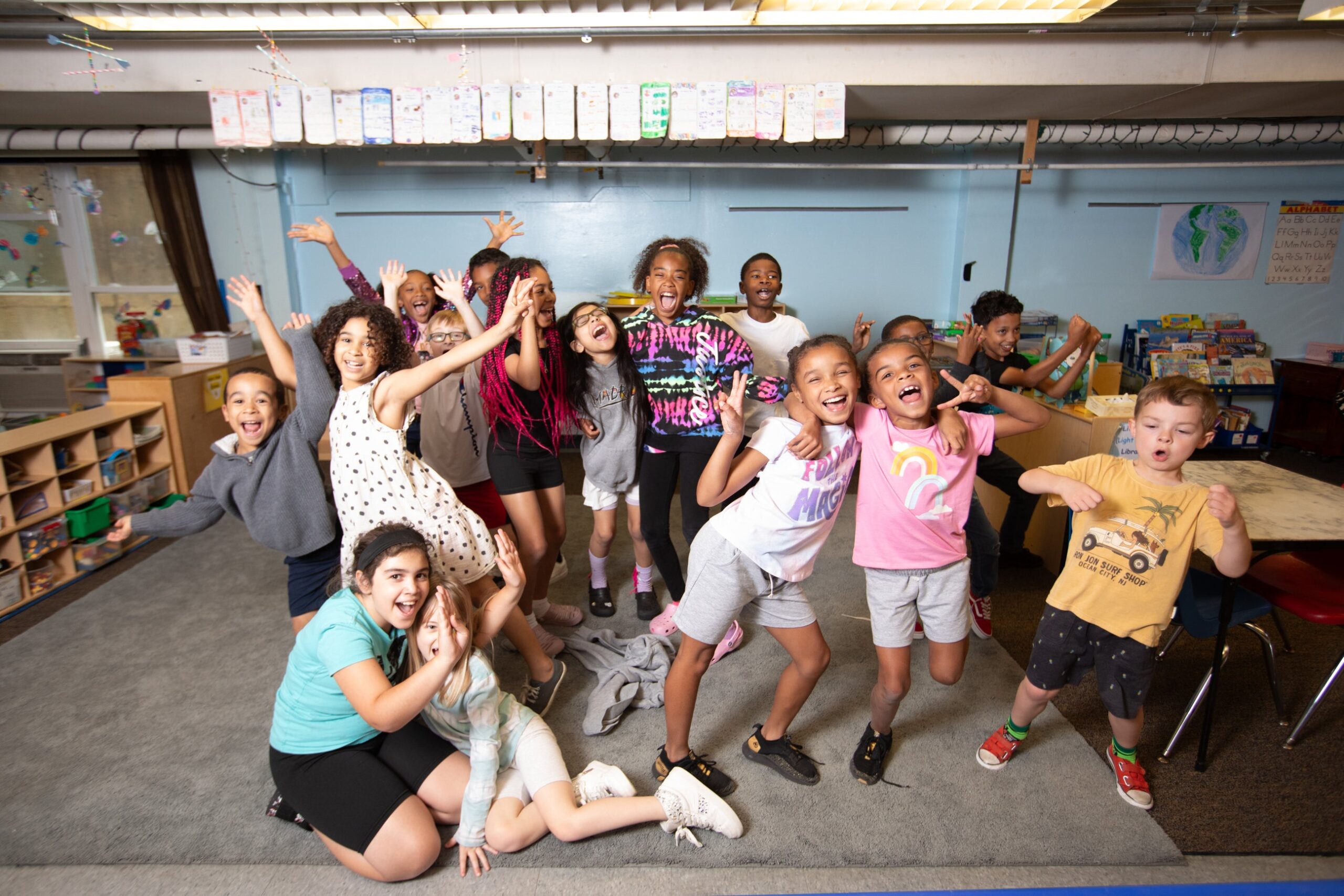 A group of school-aged children from The Learning Center at Third Street Alliance are smiling and posing for the picture.